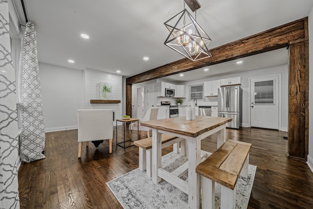 kitchen with backsplash, white cabinets, dark hardwood / wood-style floors, decorative light fixtures, and stainless steel appliances