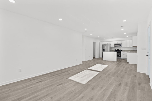 unfurnished living room featuring light hardwood / wood-style floors and sink