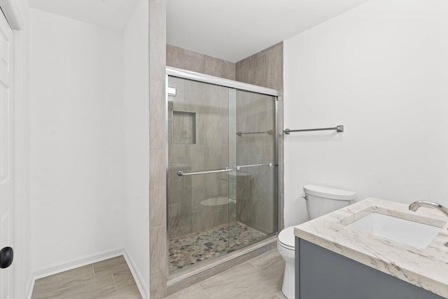 bathroom featuring vanity, toilet, and a shower with shower door