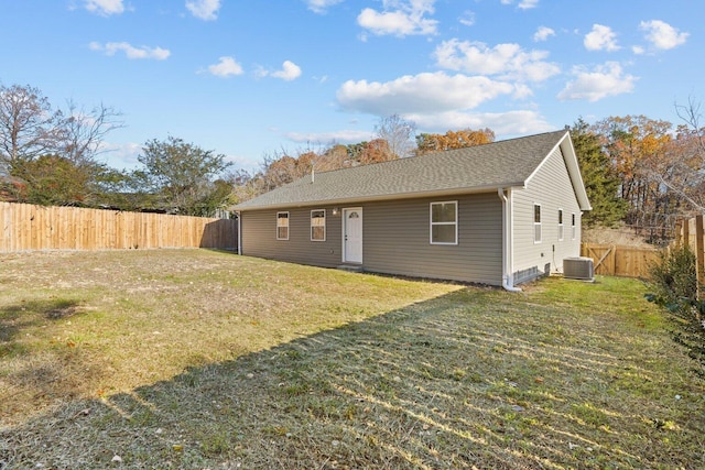 rear view of property featuring cooling unit and a yard