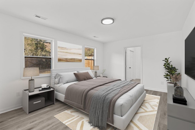 bedroom with light hardwood / wood-style floors and multiple windows