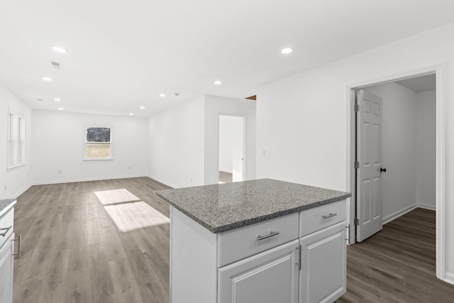 kitchen with light wood-type flooring, a center island, white cabinetry, and stone countertops