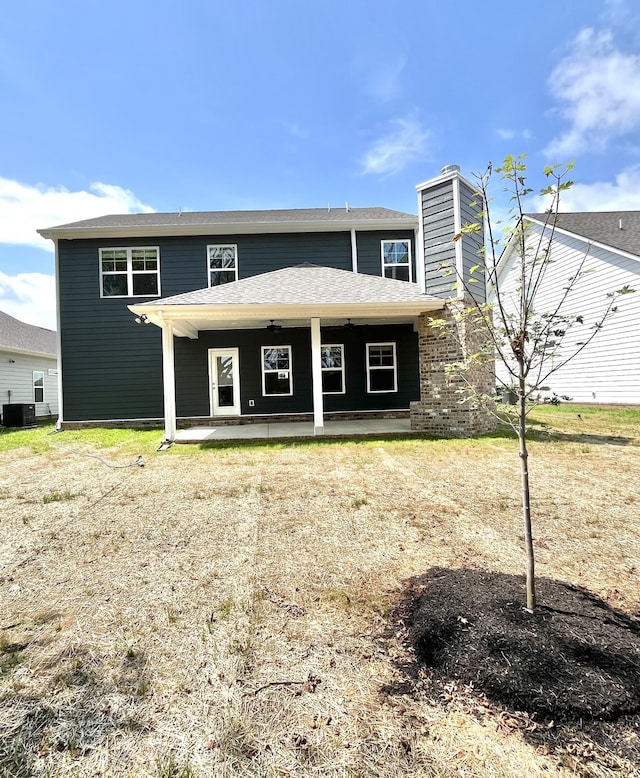 view of front of home with central AC, a chimney, and roof with shingles