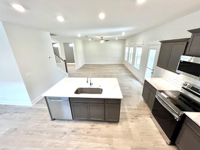 kitchen with an island with sink, appliances with stainless steel finishes, light hardwood / wood-style floors, and sink