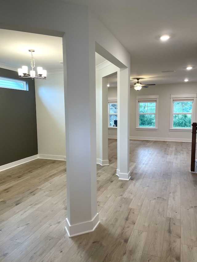 unfurnished room with crown molding, ceiling fan with notable chandelier, and light wood-type flooring