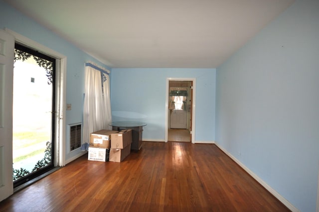 empty room featuring a wealth of natural light and dark wood-type flooring