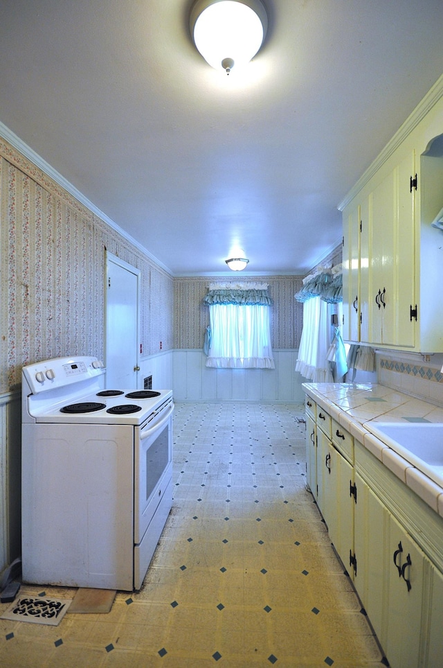 kitchen with tile countertops, sink, ornamental molding, and white electric range