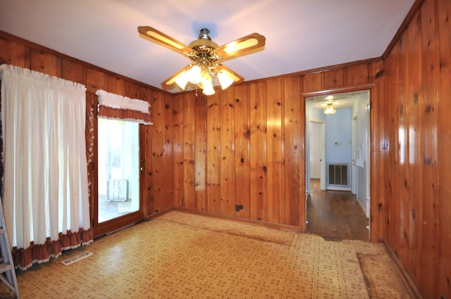 unfurnished room with wooden walls, hardwood / wood-style flooring, ceiling fan, and ornamental molding