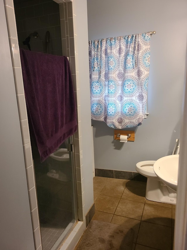 bathroom with tile patterned floors, toilet, and a shower with door