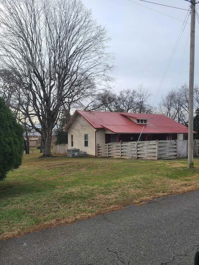 view of side of property with central AC unit and a yard