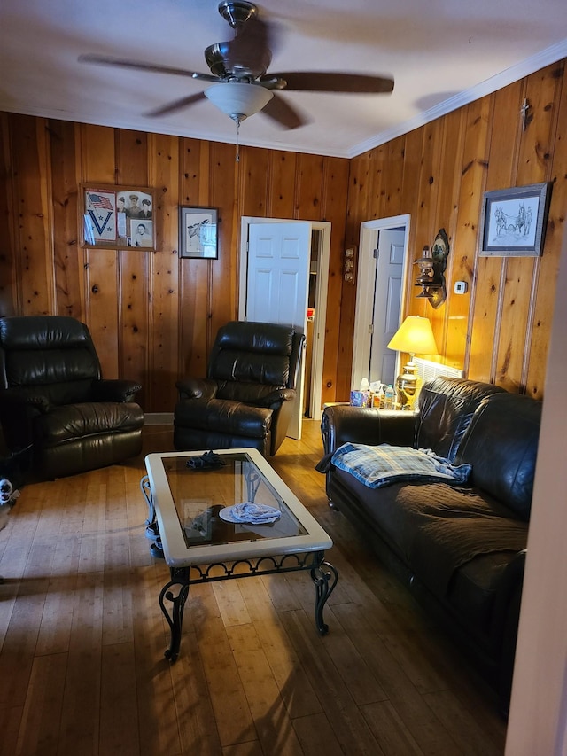 living room featuring hardwood / wood-style flooring, ceiling fan, ornamental molding, and wood walls