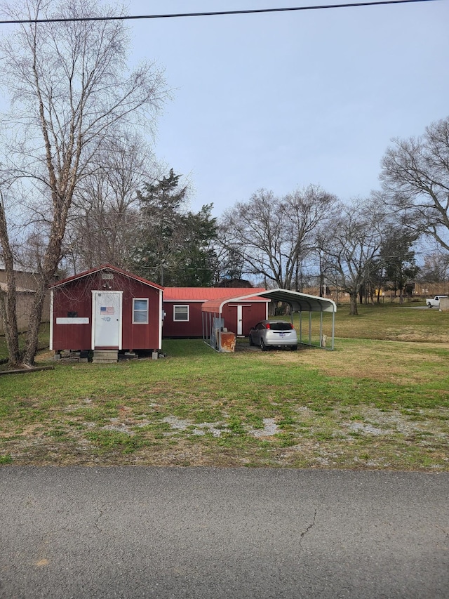 view of front of home featuring a carport, an outbuilding, and a front lawn