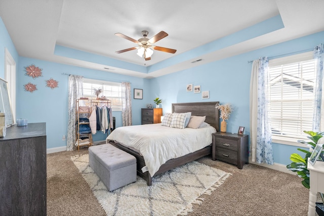 bedroom featuring light colored carpet, ceiling fan, and a tray ceiling