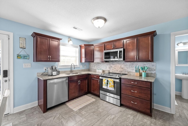 kitchen featuring light stone countertops, appliances with stainless steel finishes, tasteful backsplash, and sink