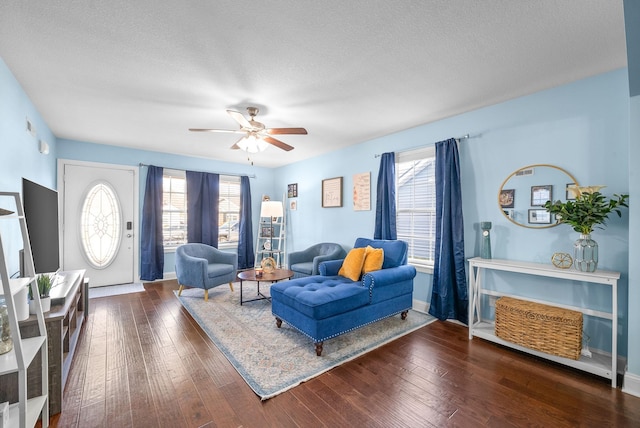 living room featuring a textured ceiling, ceiling fan, plenty of natural light, and dark wood-type flooring