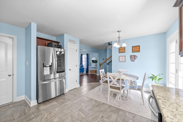 kitchen featuring light stone countertops, stainless steel appliances, decorative light fixtures, and a chandelier