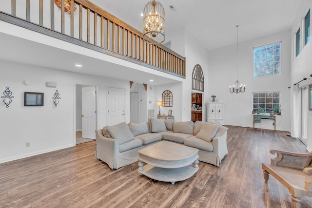 living room with an inviting chandelier, a towering ceiling, and hardwood / wood-style flooring