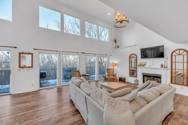 living room featuring hardwood / wood-style flooring, a healthy amount of sunlight, a high ceiling, and an inviting chandelier