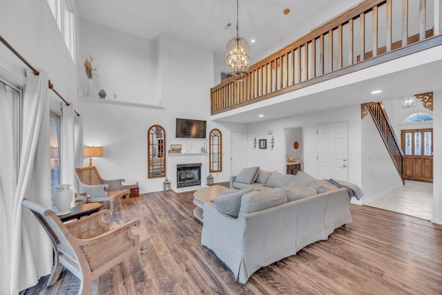 living room with a notable chandelier, a high ceiling, a fireplace, wood finished floors, and baseboards