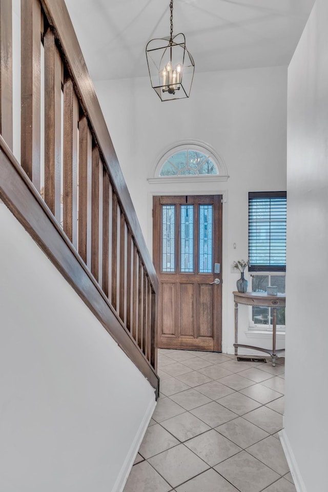 entryway featuring a chandelier, light tile patterned floors, baseboards, and stairs