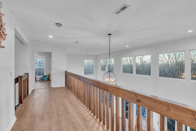 hallway with a chandelier and light hardwood / wood-style floors