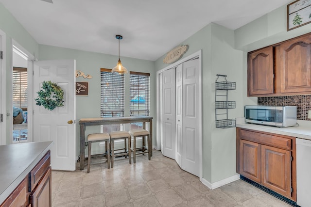 kitchen featuring dishwasher, backsplash, and hanging light fixtures