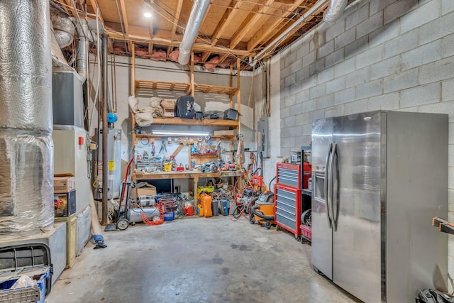 basement with a workshop area, stainless steel refrigerator with ice dispenser, electric panel, and water heater