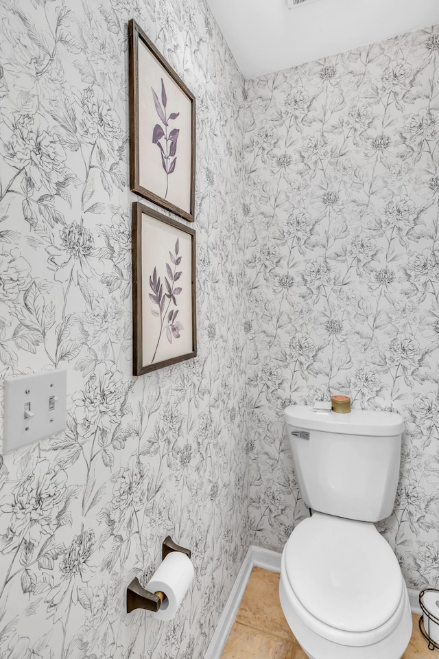 bathroom with toilet, wallpapered walls, baseboards, and tile patterned floors