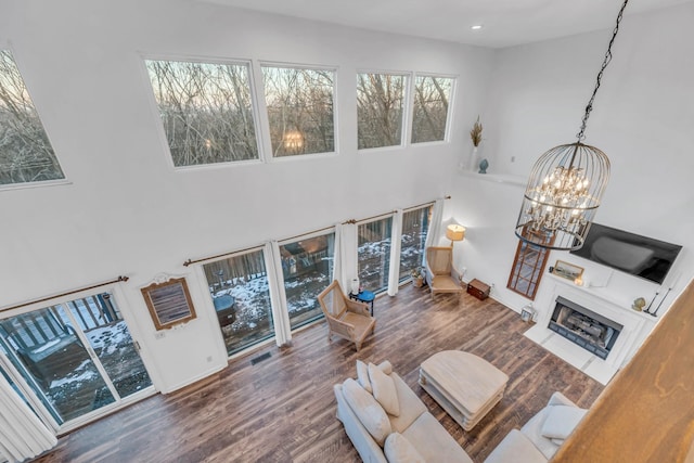 living area featuring recessed lighting, a fireplace with flush hearth, wood finished floors, a chandelier, and baseboards