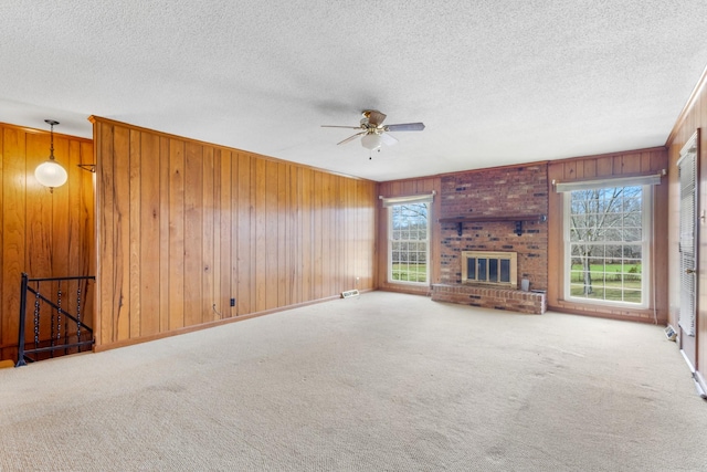 unfurnished living room featuring carpet, a healthy amount of sunlight, and wooden walls