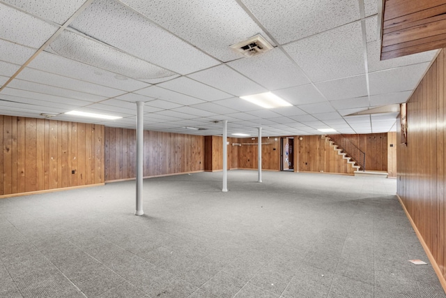 basement with a paneled ceiling and wooden walls