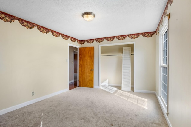 unfurnished bedroom featuring multiple windows, a textured ceiling, light colored carpet, and a closet