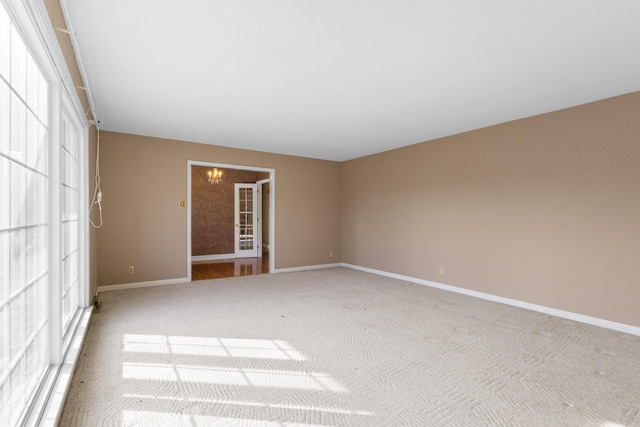 carpeted spare room with a chandelier