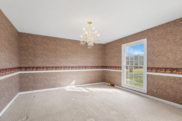 empty room featuring a notable chandelier and carpet floors