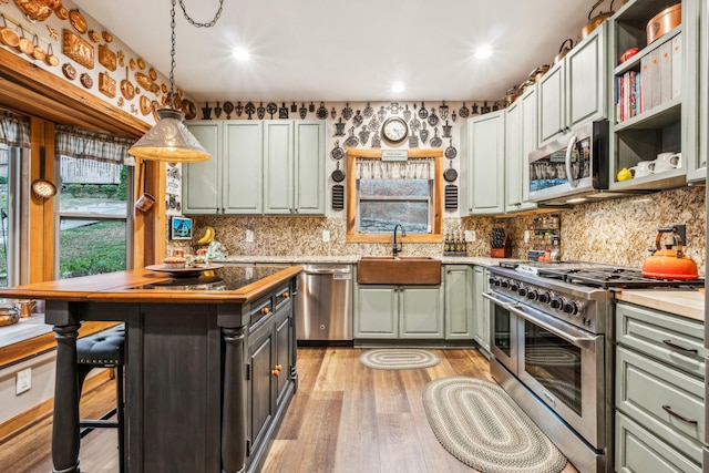 kitchen with appliances with stainless steel finishes, light wood-type flooring, sink, pendant lighting, and a kitchen island