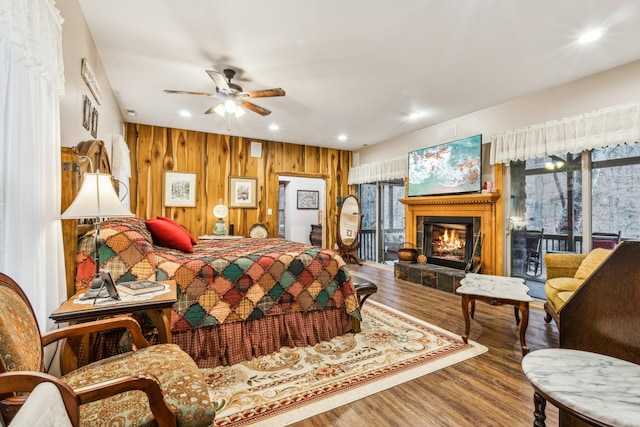 bedroom featuring hardwood / wood-style floors, wood walls, and access to exterior