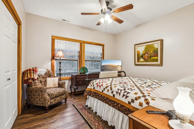 bedroom with dark wood-type flooring, ceiling fan, and a closet