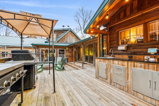 wooden terrace with area for grilling, sink, and grilling area