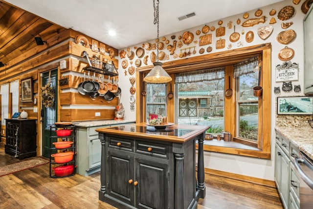 kitchen with hanging light fixtures, a center island, stainless steel dishwasher, and light hardwood / wood-style flooring