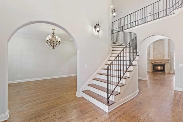 staircase featuring wood-type flooring, an inviting chandelier, and ornamental molding