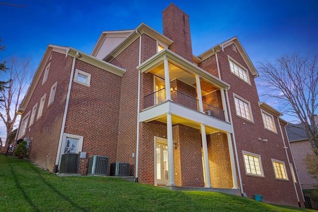 back of house with a balcony, a yard, and central AC