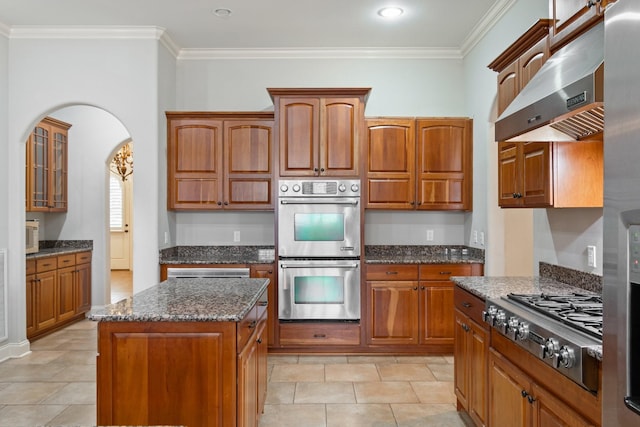 kitchen with crown molding, a center island, range hood, and appliances with stainless steel finishes