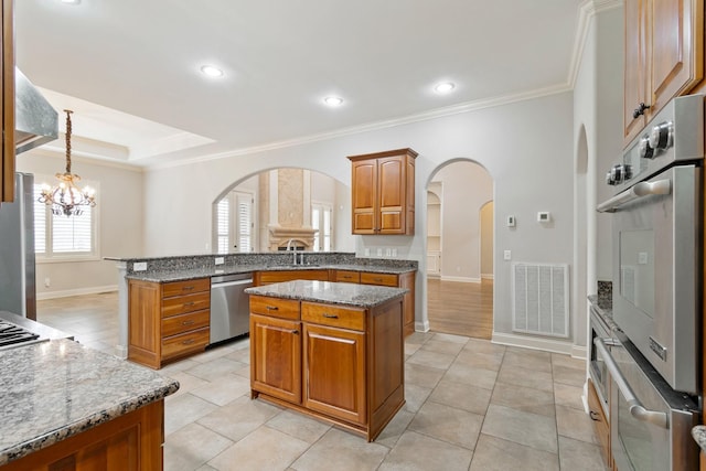 kitchen featuring light stone countertops, a chandelier, a center island, and stainless steel appliances