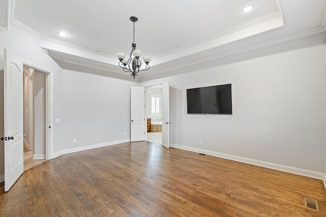 unfurnished room featuring dark wood-type flooring, crown molding, a tray ceiling, and a notable chandelier