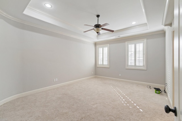 carpeted spare room featuring a raised ceiling, ceiling fan, and ornamental molding