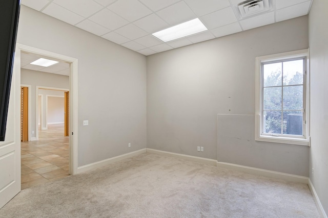 empty room featuring a paneled ceiling and light carpet