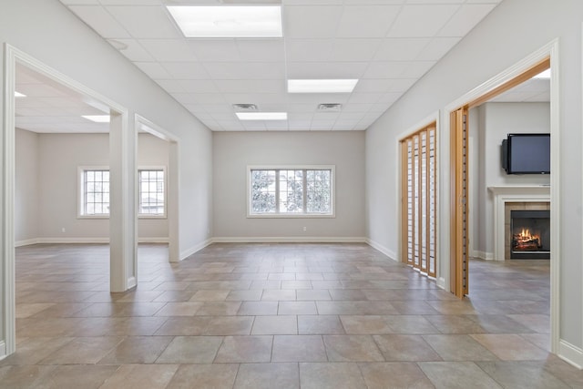 unfurnished room featuring a tile fireplace and a paneled ceiling