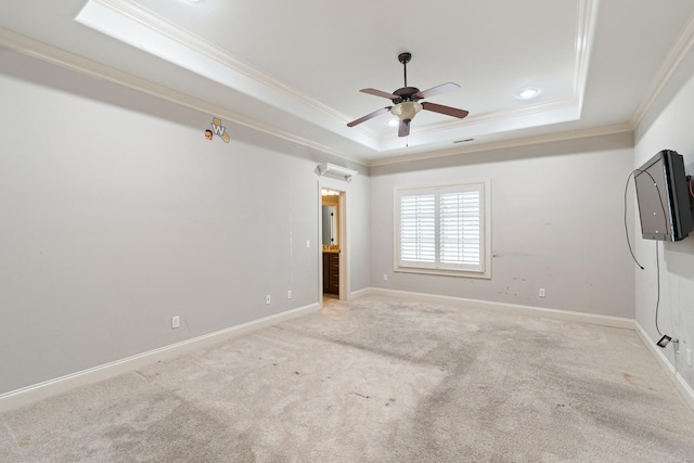 empty room featuring ceiling fan, a raised ceiling, ornamental molding, and light carpet