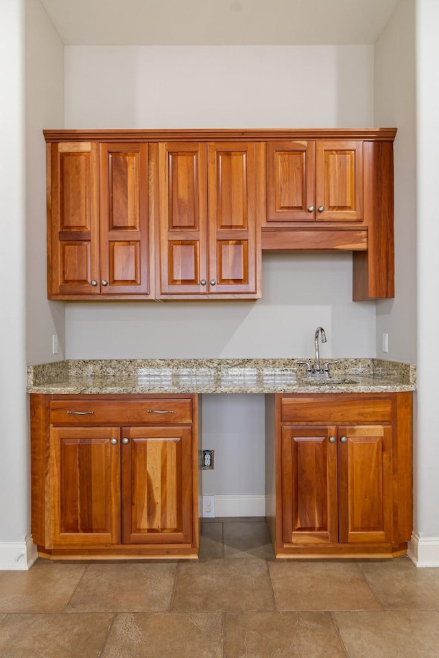 kitchen featuring light stone counters and sink