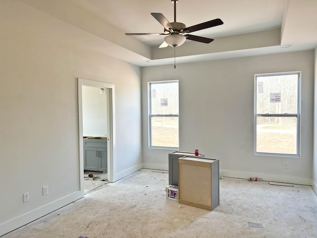 unfurnished room featuring ceiling fan, baseboards, and a raised ceiling